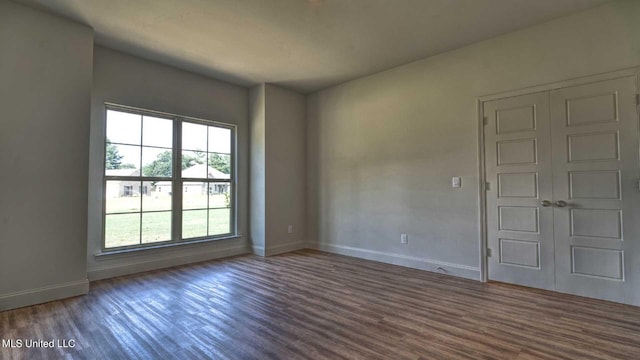 unfurnished room with dark wood-type flooring