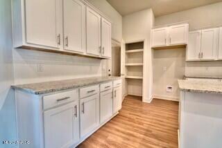 kitchen featuring light stone countertops, white cabinetry, and light hardwood / wood-style flooring