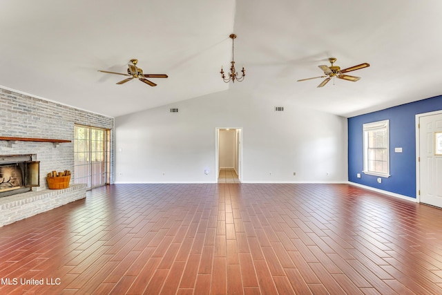 unfurnished living room featuring ceiling fan with notable chandelier, vaulted ceiling, and a brick fireplace