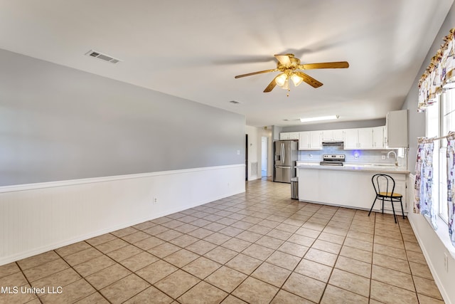 kitchen with ceiling fan, light tile patterned flooring, kitchen peninsula, white cabinets, and appliances with stainless steel finishes