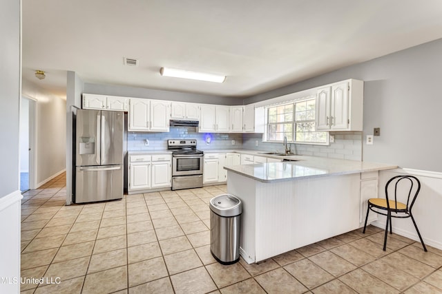 kitchen with white cabinets, light tile patterned flooring, kitchen peninsula, and stainless steel appliances