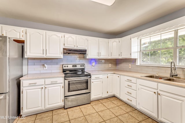 kitchen featuring sink, stainless steel appliances, light tile patterned floors, decorative backsplash, and white cabinets