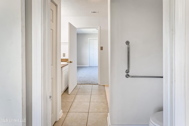 bathroom featuring tile patterned flooring, vanity, toilet, and a textured ceiling