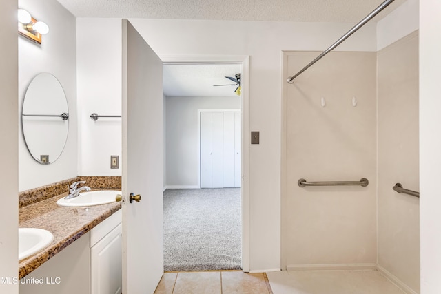 bathroom with tile patterned floors, ceiling fan, vanity, and a textured ceiling