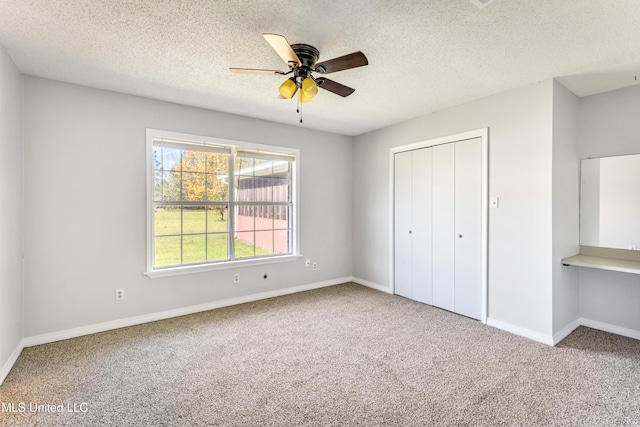 unfurnished bedroom with carpet flooring, a textured ceiling, a closet, and ceiling fan