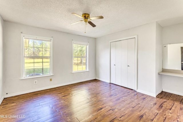 unfurnished bedroom featuring ceiling fan, a closet, dark wood-type flooring, and a textured ceiling