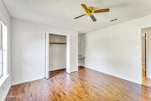 unfurnished bedroom with hardwood / wood-style flooring, ceiling fan, and a textured ceiling