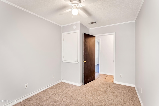 unfurnished bedroom with ceiling fan, light colored carpet, ornamental molding, and a textured ceiling