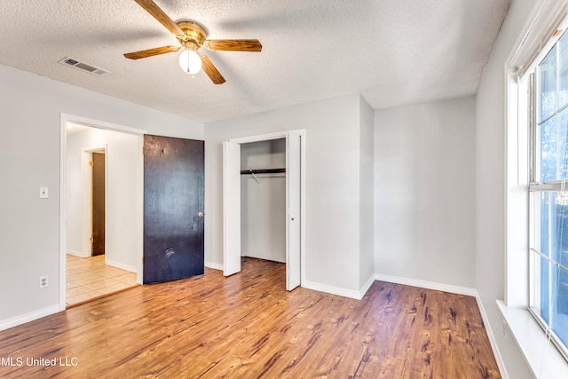 unfurnished bedroom featuring ceiling fan, light hardwood / wood-style floors, a textured ceiling, and a closet