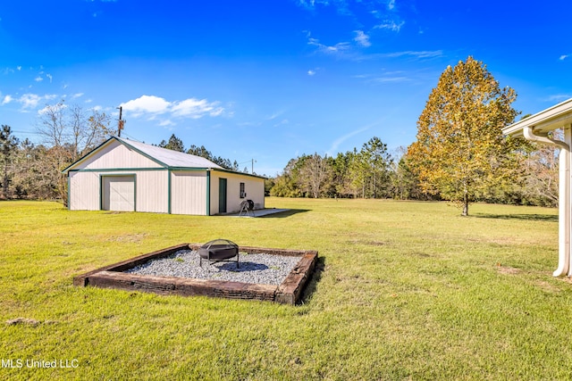 view of yard with an outbuilding, a garage, and an outdoor fire pit