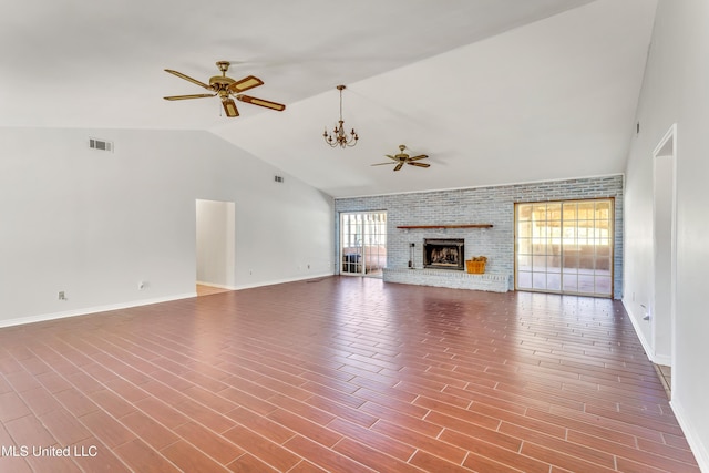 unfurnished living room featuring a fireplace, ceiling fan with notable chandelier, brick wall, and lofted ceiling