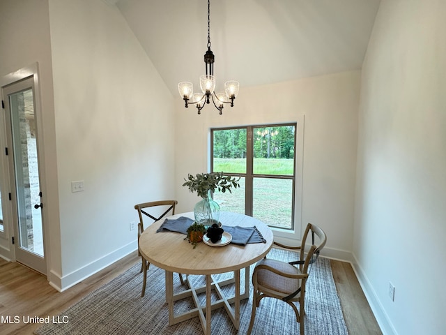 dining space featuring high vaulted ceiling, a chandelier, and wood-type flooring