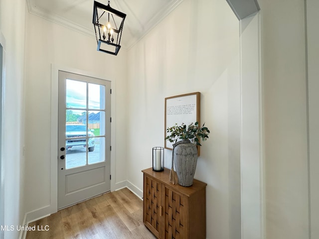 doorway to outside with ornamental molding, light hardwood / wood-style flooring, and a chandelier