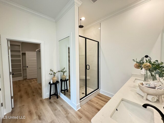 bathroom with a shower with door, vanity, crown molding, and wood-type flooring