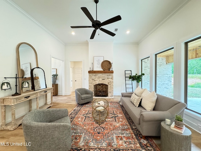 living room featuring ornamental molding, a stone fireplace, hardwood / wood-style flooring, and ceiling fan