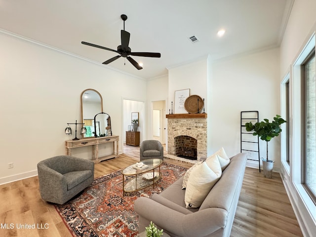 living room featuring crown molding, a brick fireplace, light hardwood / wood-style floors, and ceiling fan