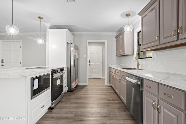 kitchen featuring a sink, appliances with stainless steel finishes, gray cabinetry, crown molding, and backsplash