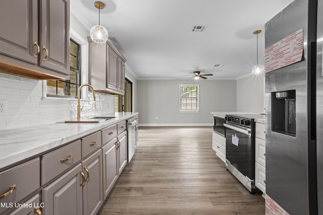 kitchen featuring stainless steel appliances, gray cabinets, crown molding, a sink, and baseboards