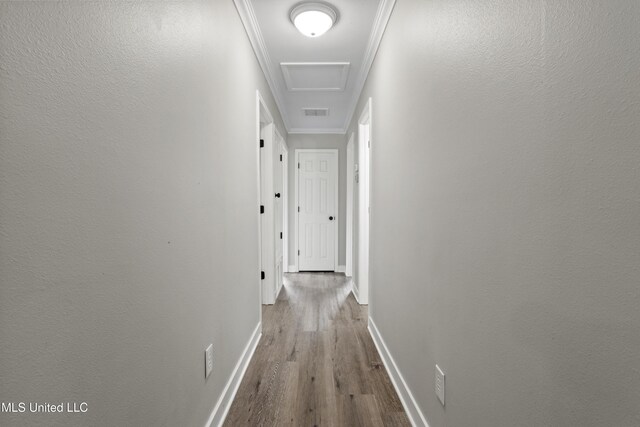 hall with wood finished floors, baseboards, attic access, and ornamental molding