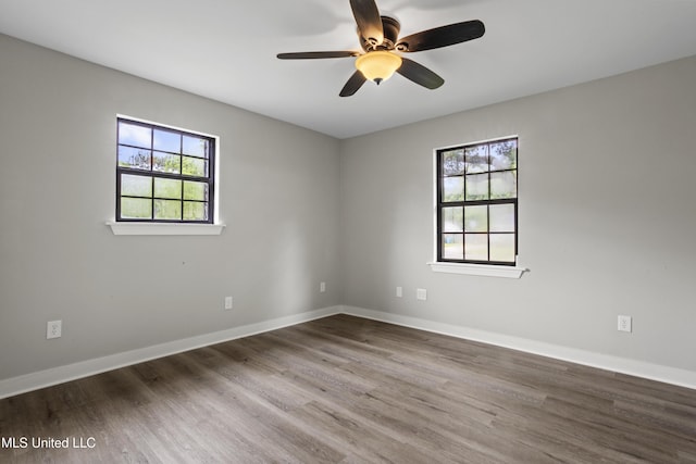 empty room with ceiling fan, wood finished floors, and baseboards
