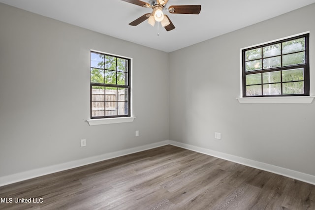 spare room featuring wood finished floors, baseboards, and ceiling fan