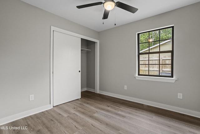 unfurnished bedroom featuring wood finished floors, a closet, baseboards, and a ceiling fan