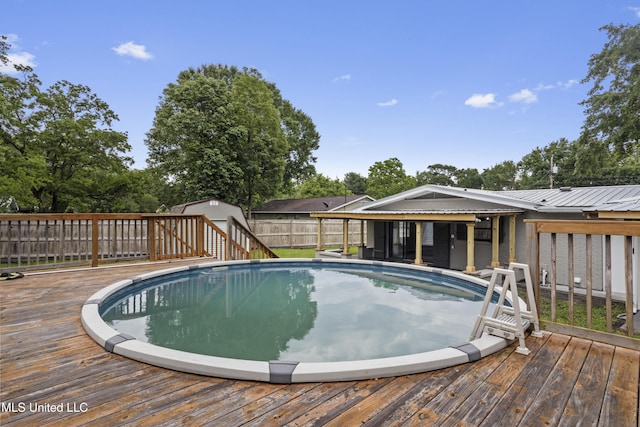 view of pool with a deck, an outdoor structure, and a storage shed