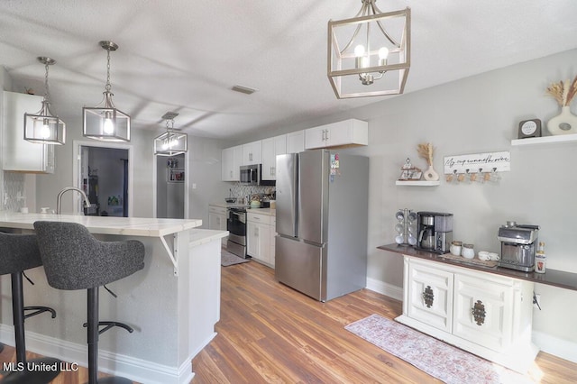 kitchen featuring white cabinetry, appliances with stainless steel finishes, dark hardwood / wood-style flooring, and decorative light fixtures