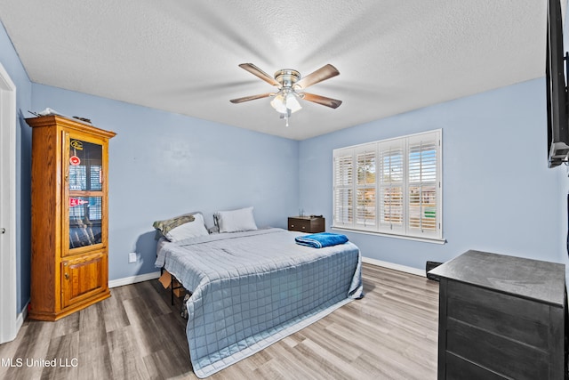 bedroom featuring ceiling fan, wood-type flooring, and a textured ceiling