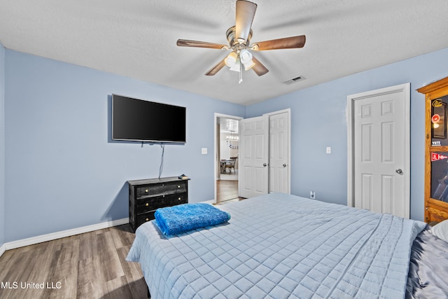 bedroom with hardwood / wood-style flooring, a textured ceiling, and ceiling fan