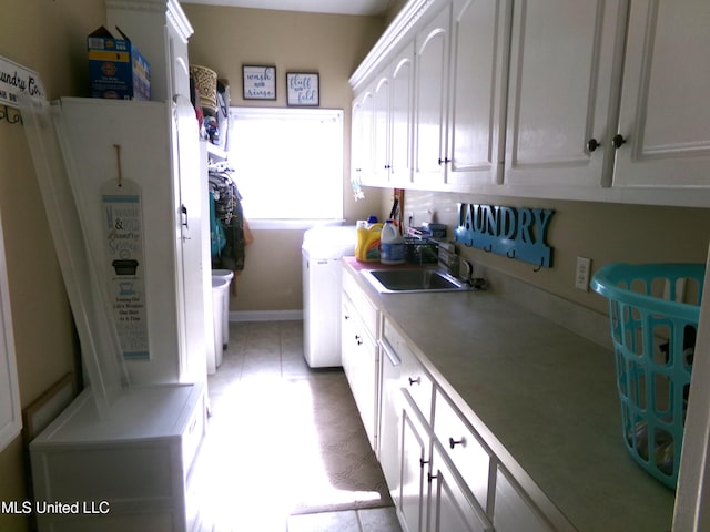 clothes washing area featuring cabinet space, washing machine and dryer, and light tile patterned floors