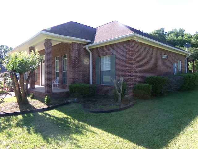 view of property exterior with brick siding, a lawn, and roof with shingles