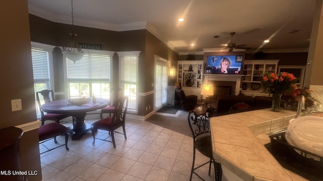 tiled dining room with ceiling fan, crown molding, a fireplace, baseboards, and recessed lighting