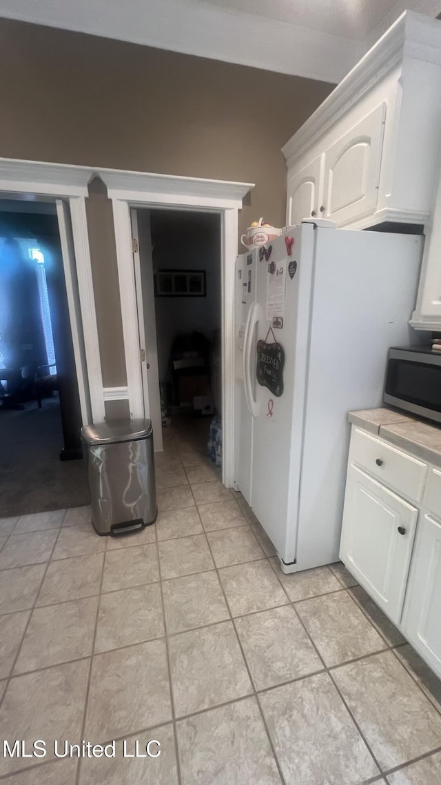 kitchen featuring stainless steel microwave, white cabinets, light tile patterned floors, and light countertops