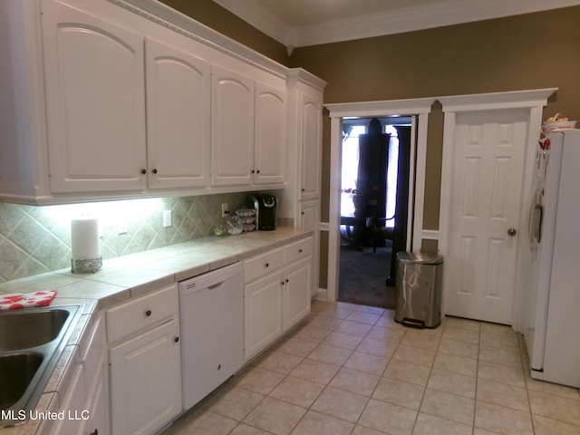 kitchen featuring white appliances, tile countertops, white cabinets, a sink, and decorative backsplash