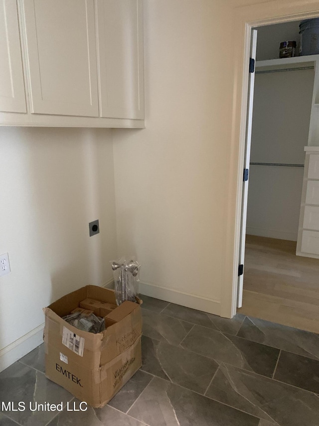 laundry area with electric dryer hookup and cabinets