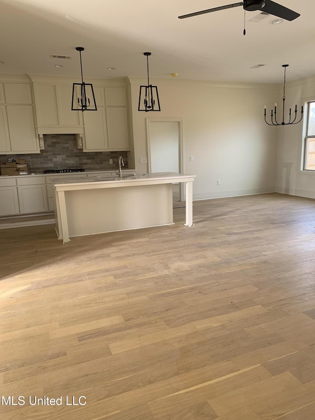 kitchen featuring pendant lighting, ceiling fan, a center island with sink, and light hardwood / wood-style flooring