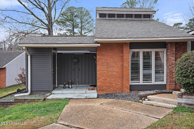 doorway to property with brick siding and a shingled roof