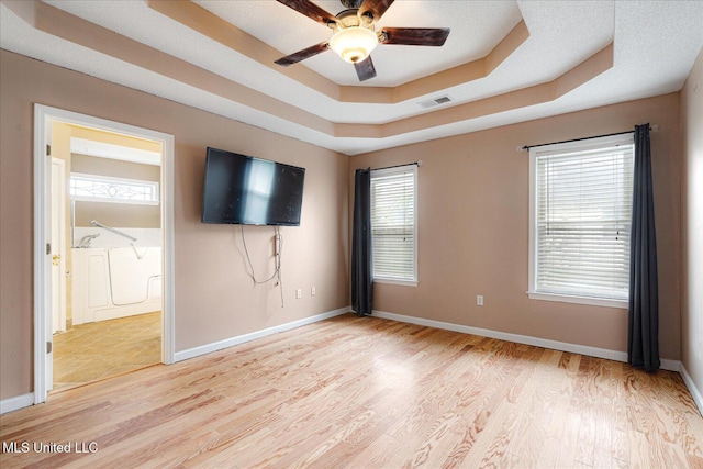 9015 Champlain Dr, Olive Branch, MS 38654 - unfurnished bedroom featuring a tray ceiling, light wood-style floors, baseboards, and connected bathroom