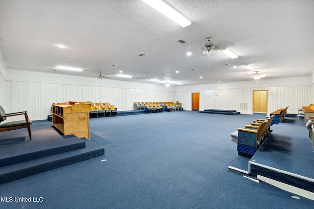 miscellaneous room featuring a textured ceiling, carpet floors, and ceiling fan