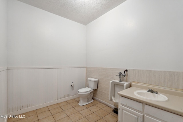 bathroom with tile patterned flooring, vanity, toilet, and a textured ceiling