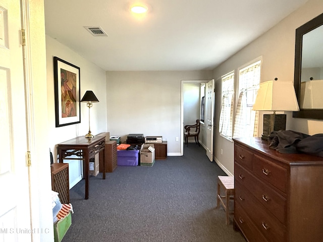 interior space featuring baseboards, visible vents, and dark colored carpet