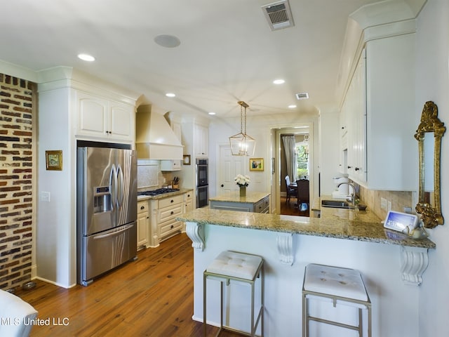 kitchen featuring kitchen peninsula, dark hardwood / wood-style flooring, custom range hood, stainless steel appliances, and hanging light fixtures