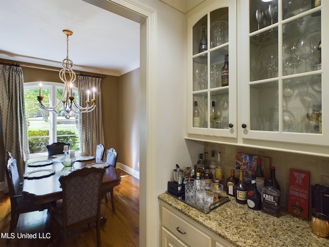 bar with white cabinetry, dark wood-type flooring, a chandelier, decorative light fixtures, and decorative backsplash