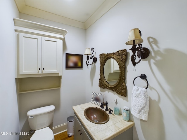 bathroom featuring toilet, vanity, wood-type flooring, and ornamental molding