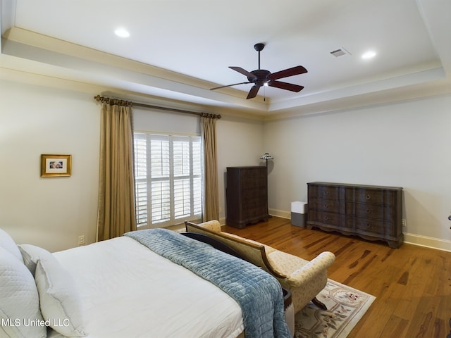 bedroom featuring a tray ceiling, ceiling fan, and wood-type flooring