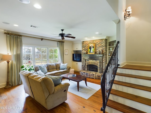 living room with ceiling fan, light wood-type flooring, and a fireplace