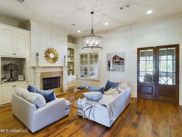 living room with a notable chandelier, dark hardwood / wood-style floors, a fireplace, and french doors