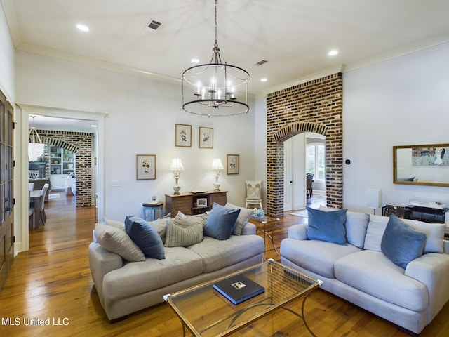 living room featuring wood-type flooring, ornamental molding, and an inviting chandelier