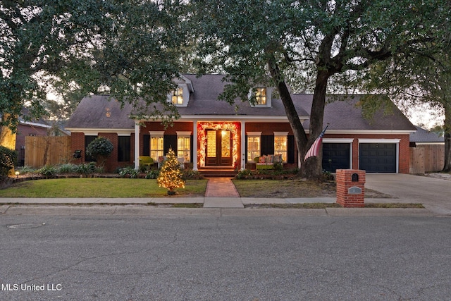 cape cod-style house with a front yard, a porch, and a garage